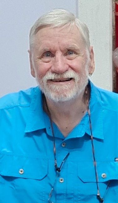 photo of Stephen Price, a white older man with a short white beard. He's smiling and wearing a Chin shirt.